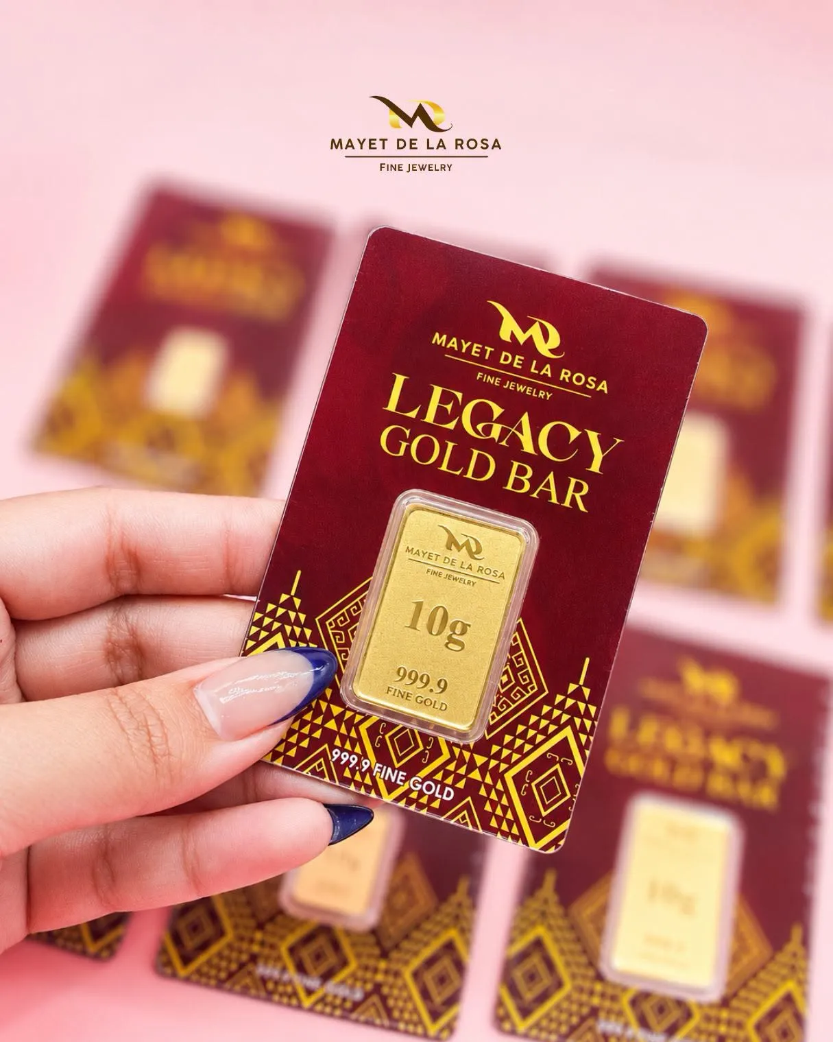 A hand holding a 10 g Legacy Gold Bar card, with more cards softly out of focus behind it